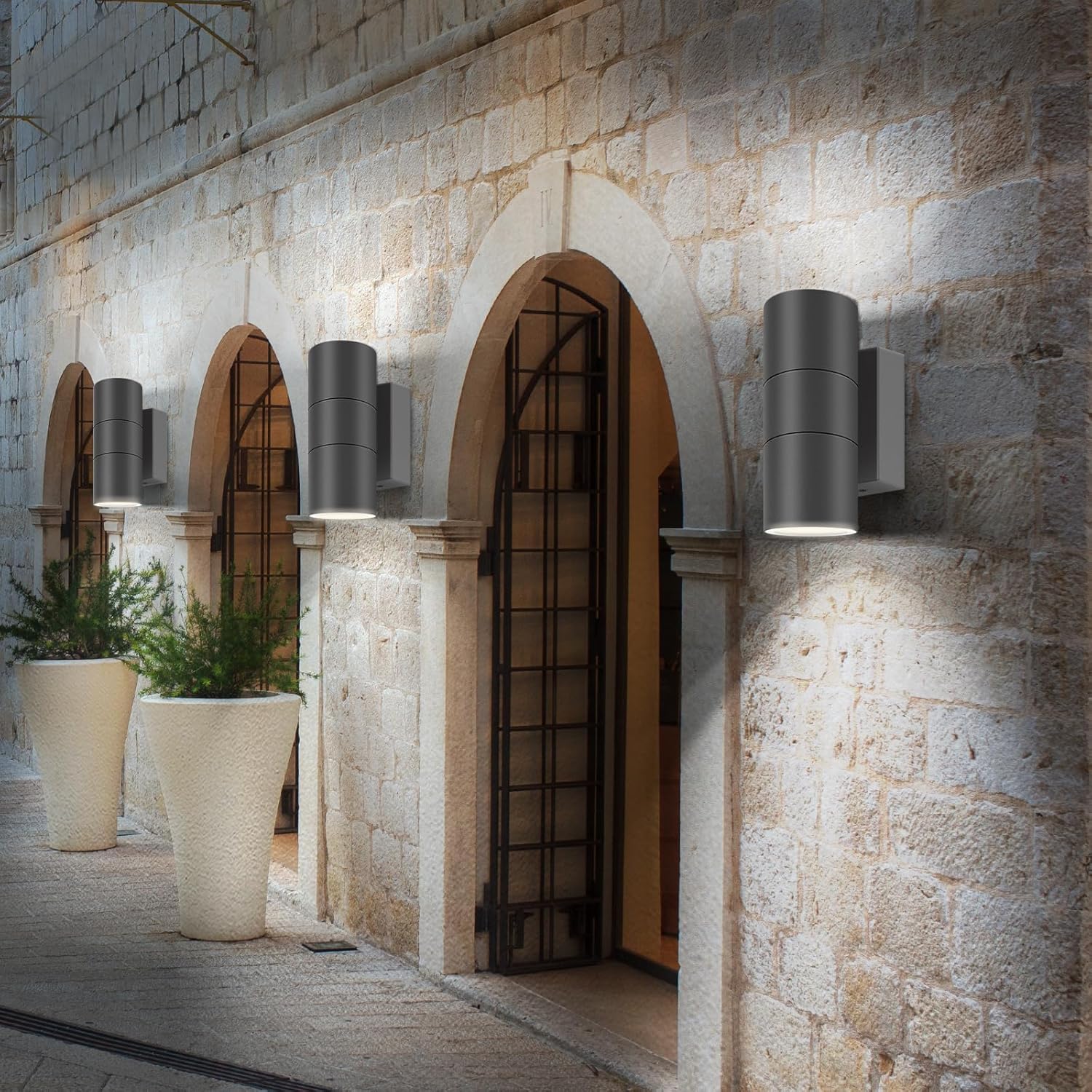 Decorative outdoor lights on a stone wall with plants and a door.