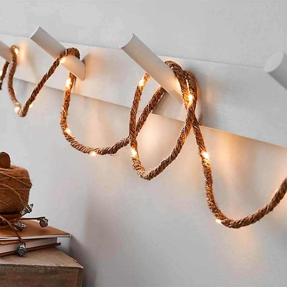 Decorative rope light fixture on a white wall with a ball of yarn and books below.