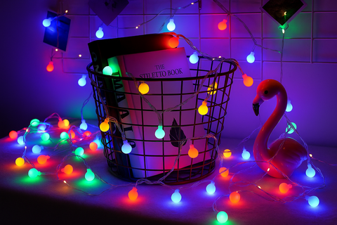 Decorative string lights with a basket and books on a tiled floor.