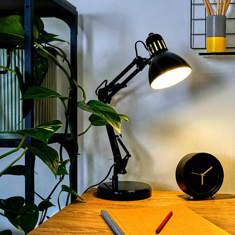 Desk lamp positioned over a computer setup in a home office.​

