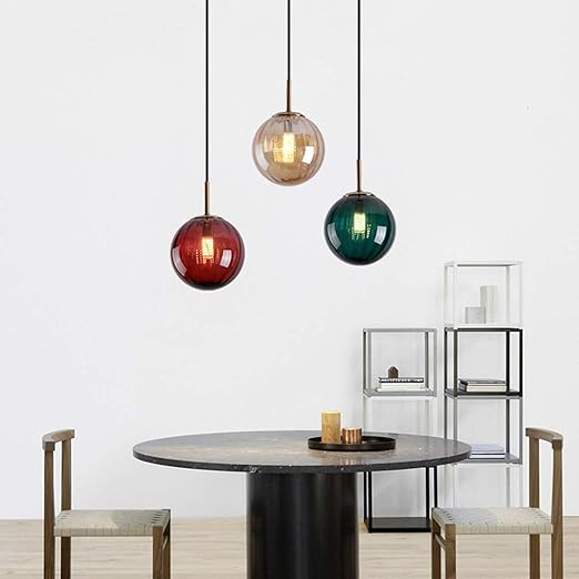 Dining area with a round table and chairs, featuring three pendant lights in different colors.