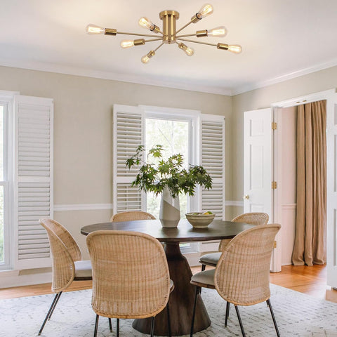 Dining room with a round wooden table and wicker chairs, featuring a modern chandelier.