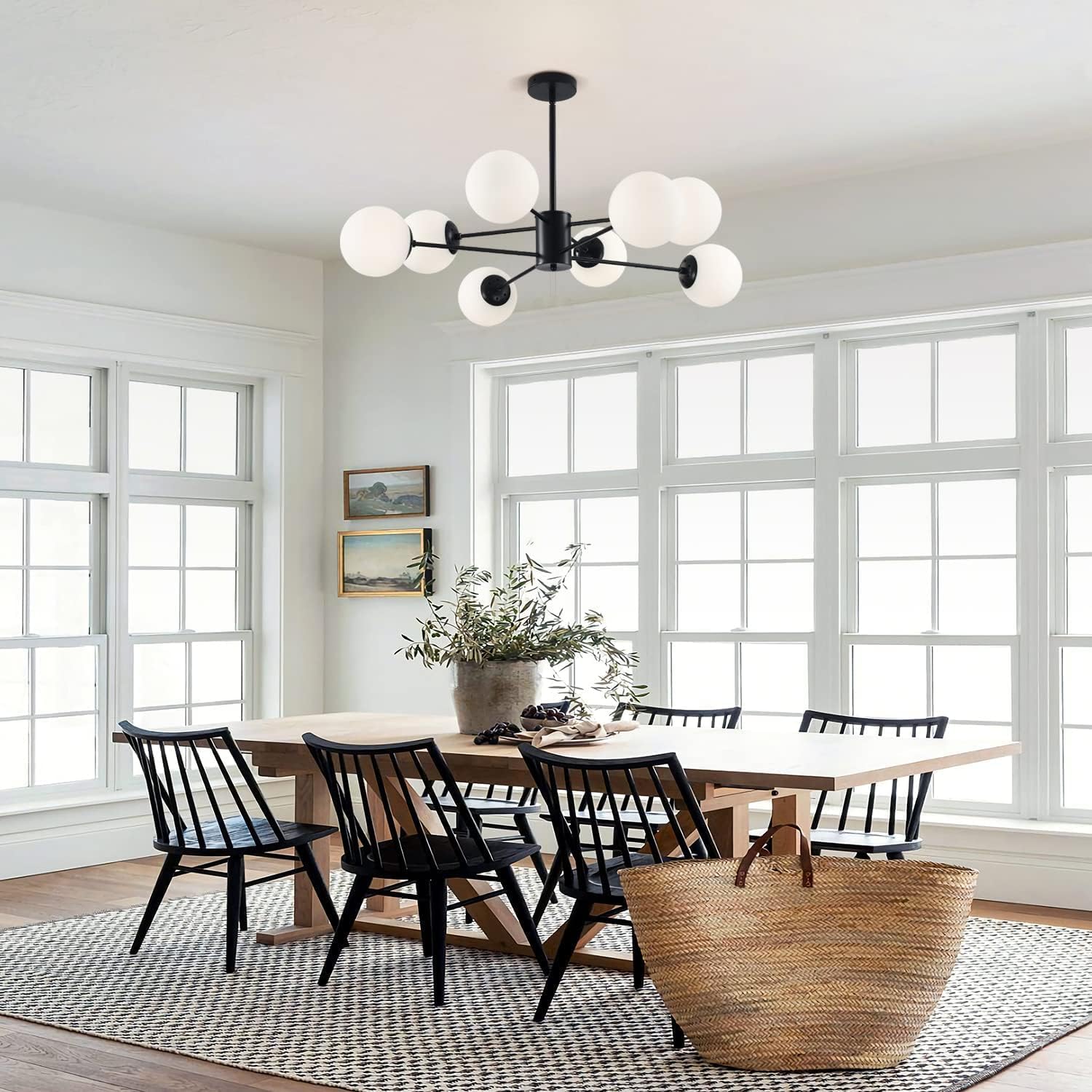 Dining room with a wooden table and black chairs, large windows, and a chandelier.
