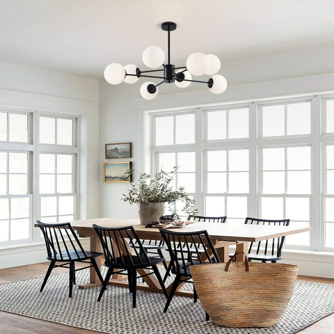 Dining room with a wooden table and black chairs, large windows, and a chandelier.