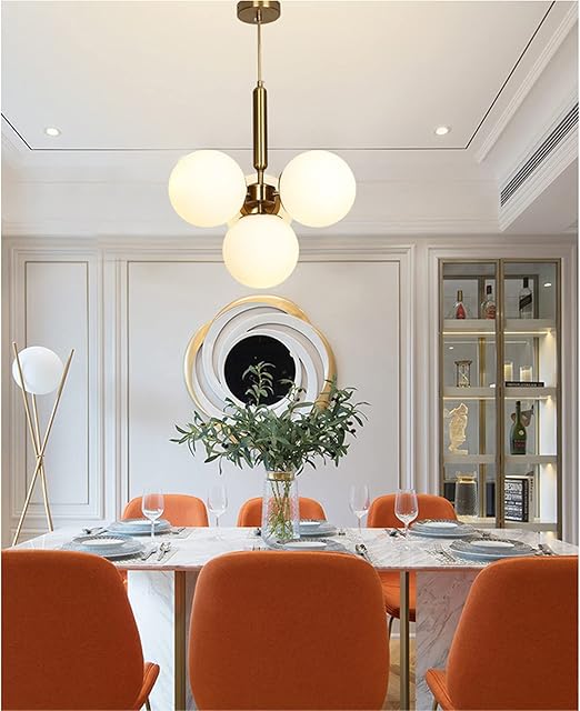 Dining room with modern pendant light, orange chairs, and a white table.