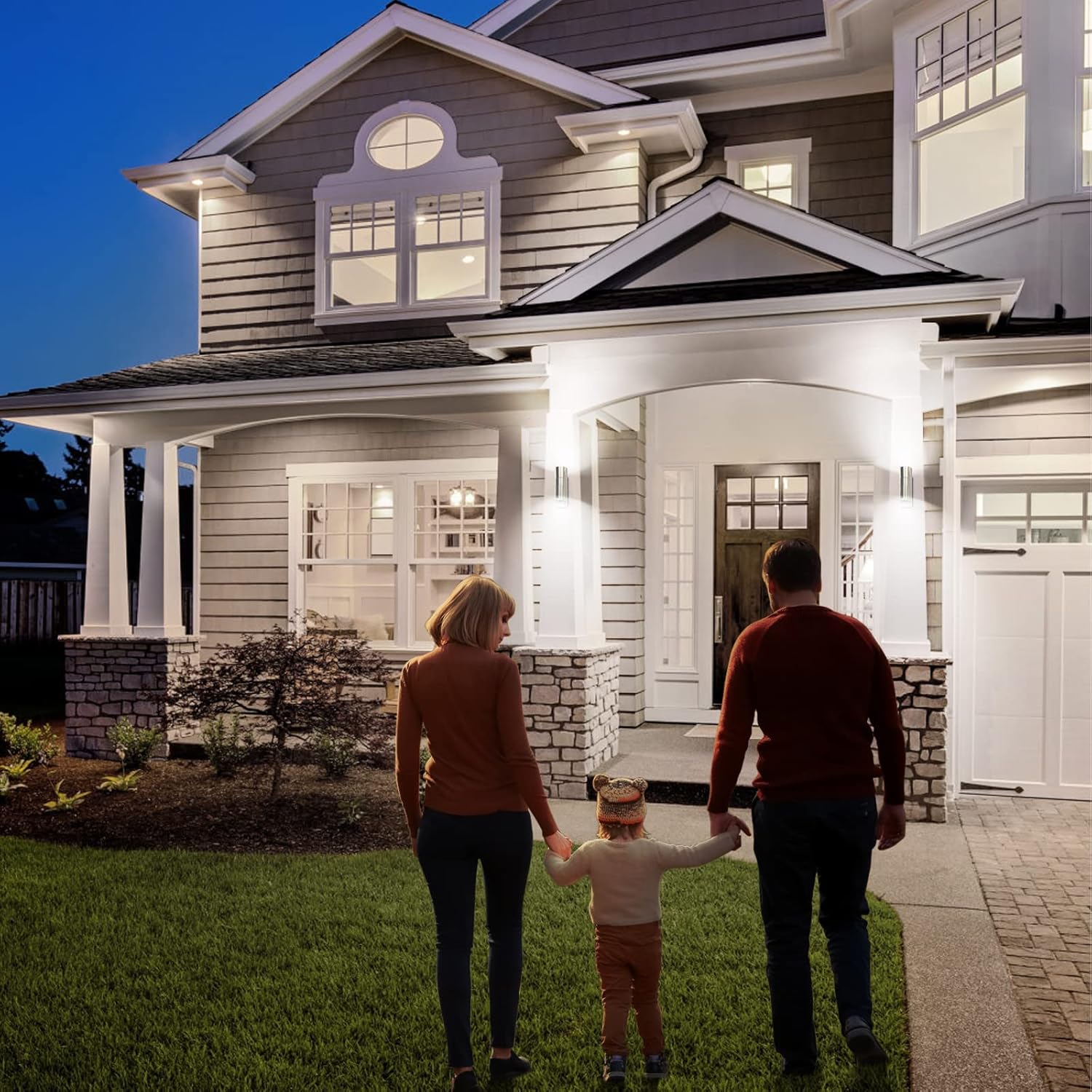 Family of three walking in front of a house at night