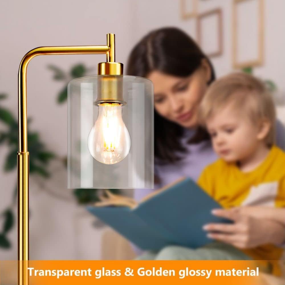 Gold floor lamp with transparent glass shade next to a woman and child reading a book.
