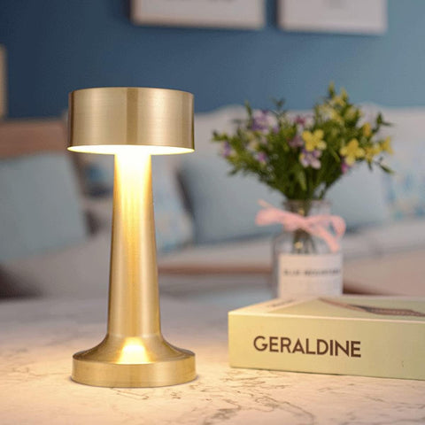 Gold table lamp on a surface with a blurred background of a room.