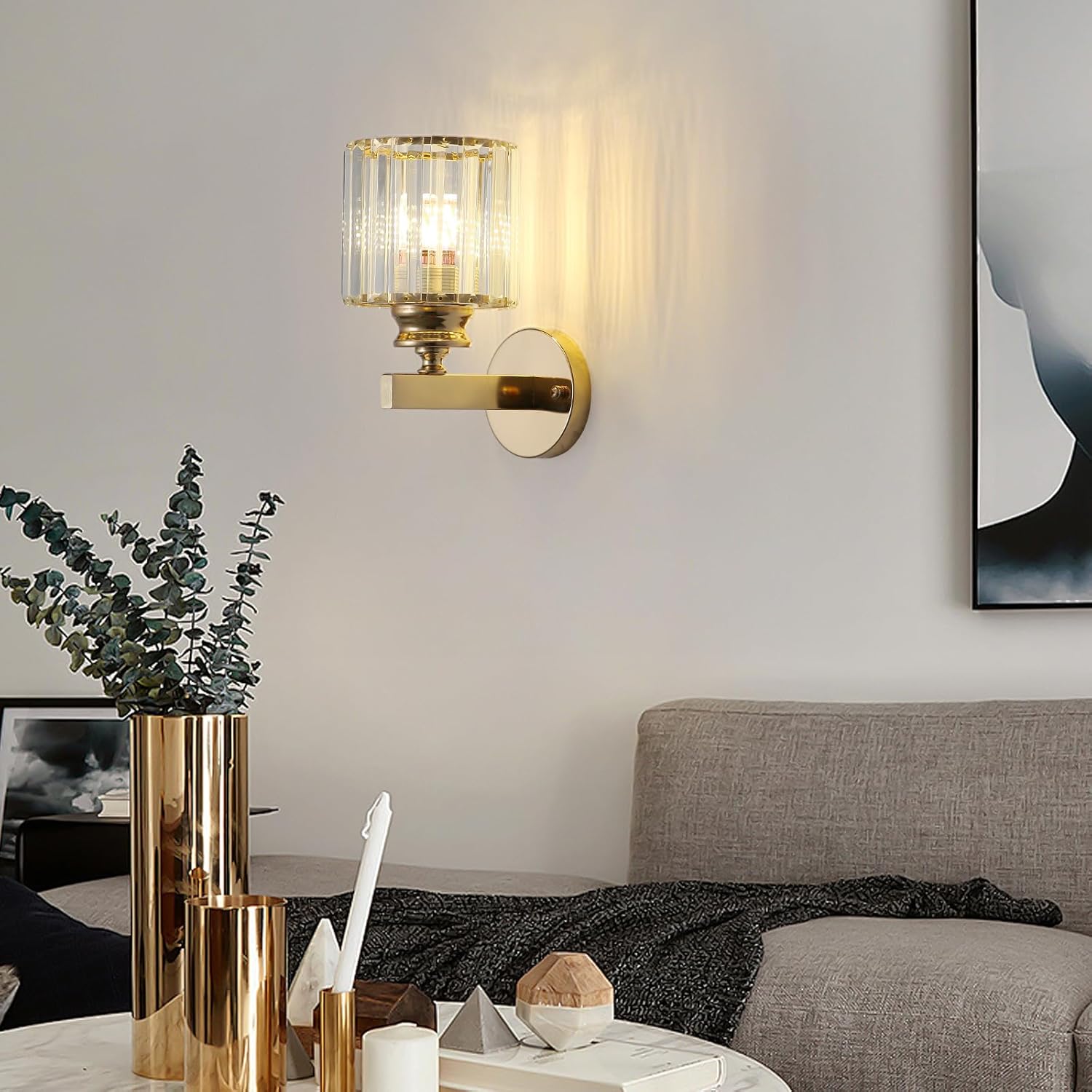 Gold wall sconce in a living room setting with a vase and decor items.