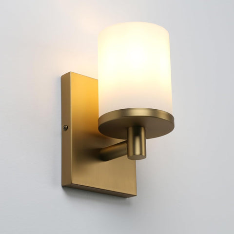 Gold wall sconce with a white shade on a gray background