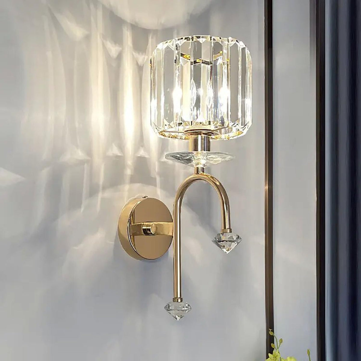 Gold wall sconce with crystal accents on a white wall