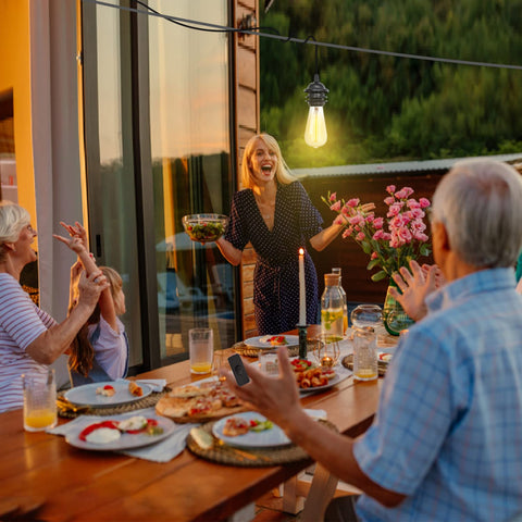 Group of people enjoying a meal outdoors with sunset in the background