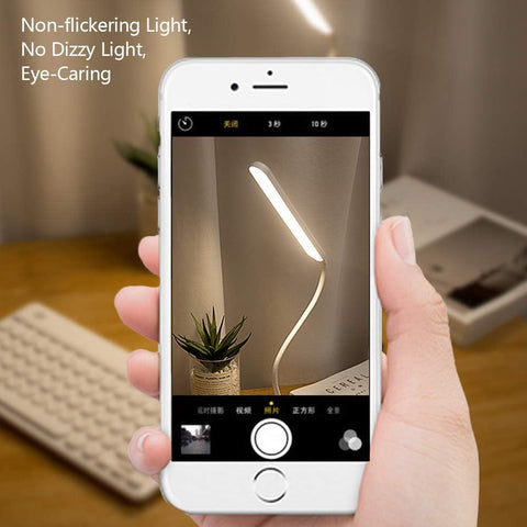 Hand holding a smartphone showing a lamp on a screen with text about non-flickering light.