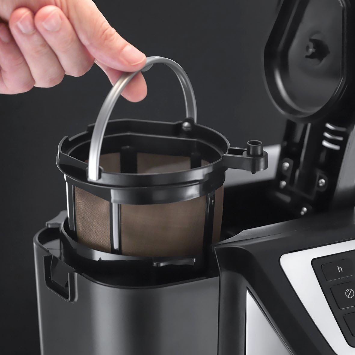 Hand placing a coffee filter into a coffee machine on a black background