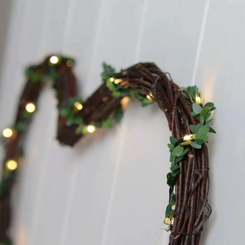 Decorative wreath with greenery and string lights on a white background