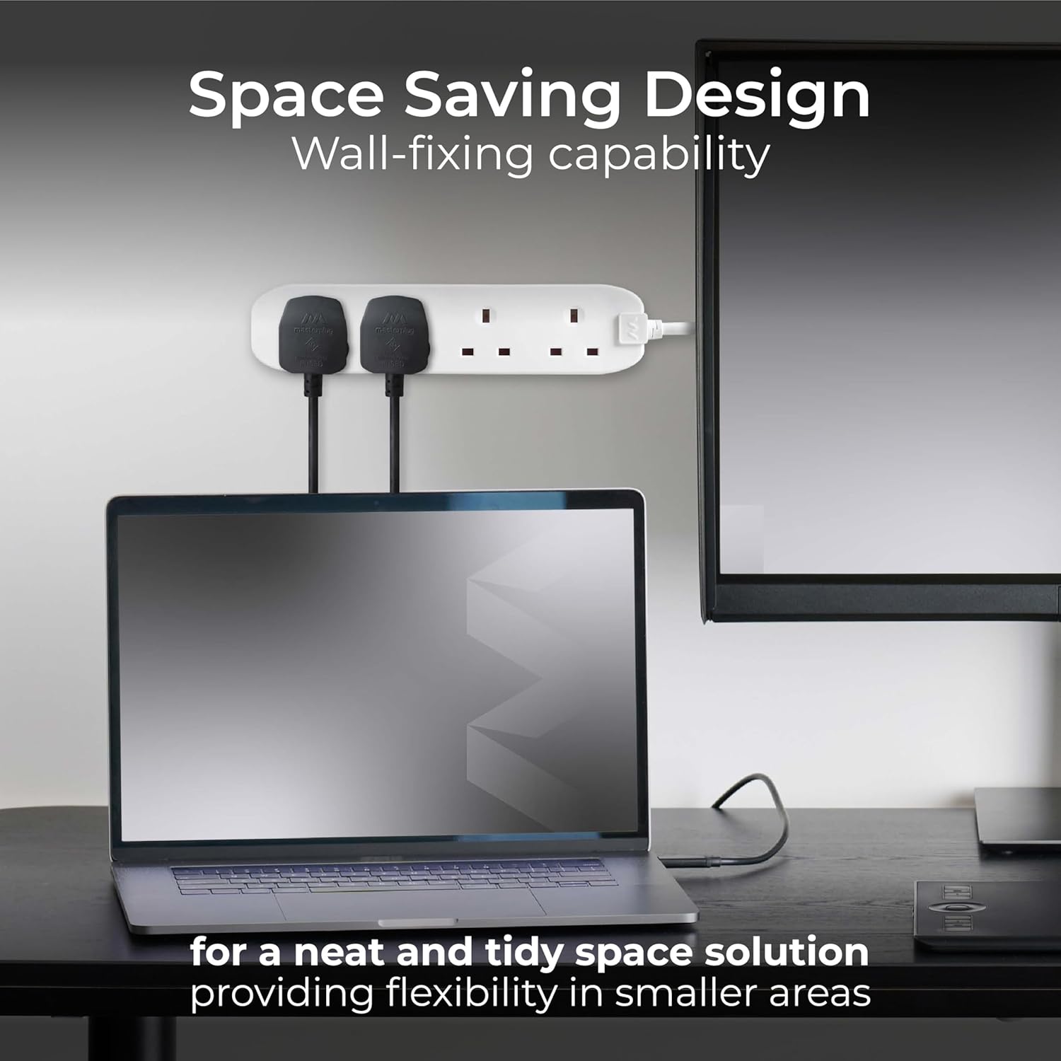 Laptop on a desk with a power strip and monitor, emphasizing space-saving design.