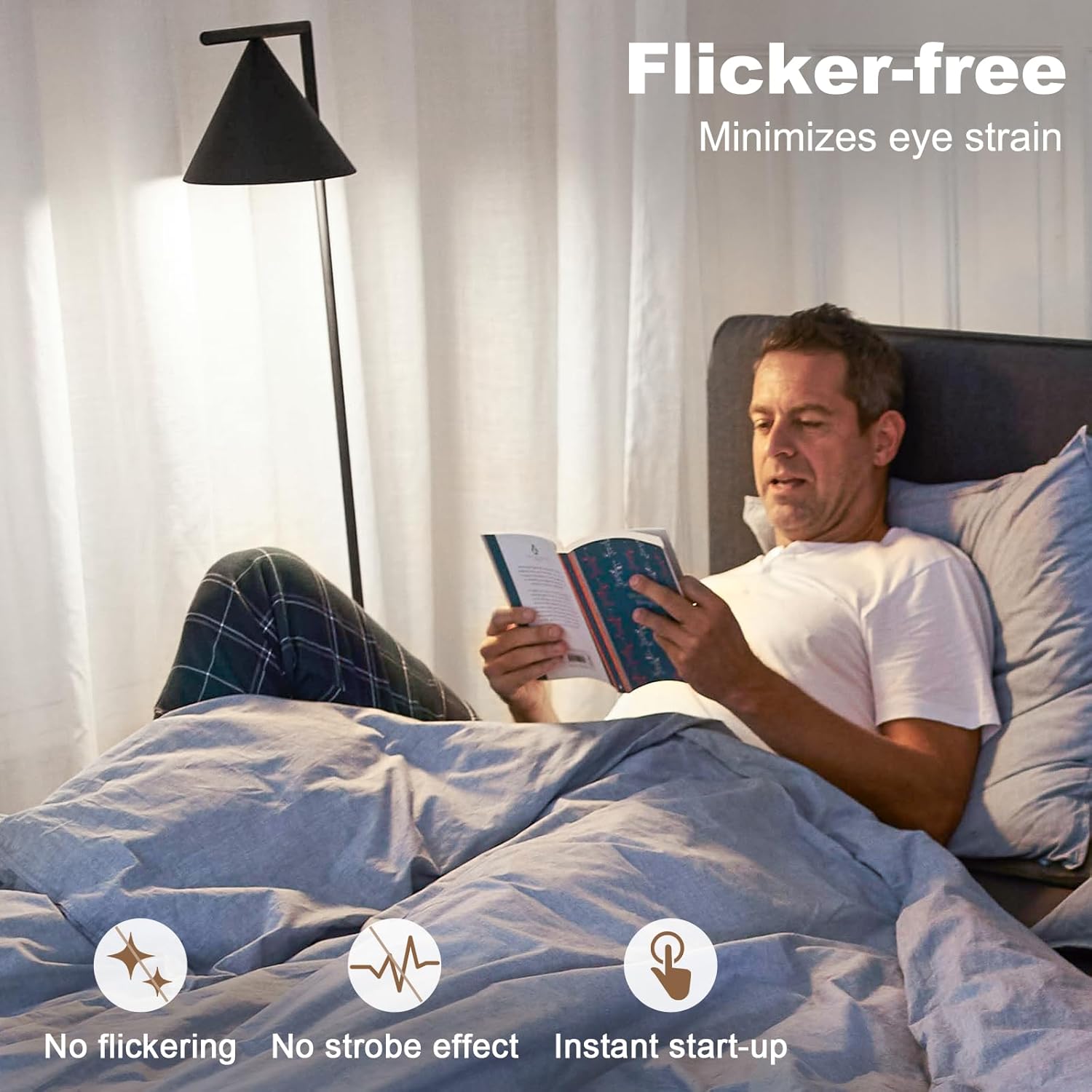 Man reading a book in bed with a 'Flicker-free' light source above him.