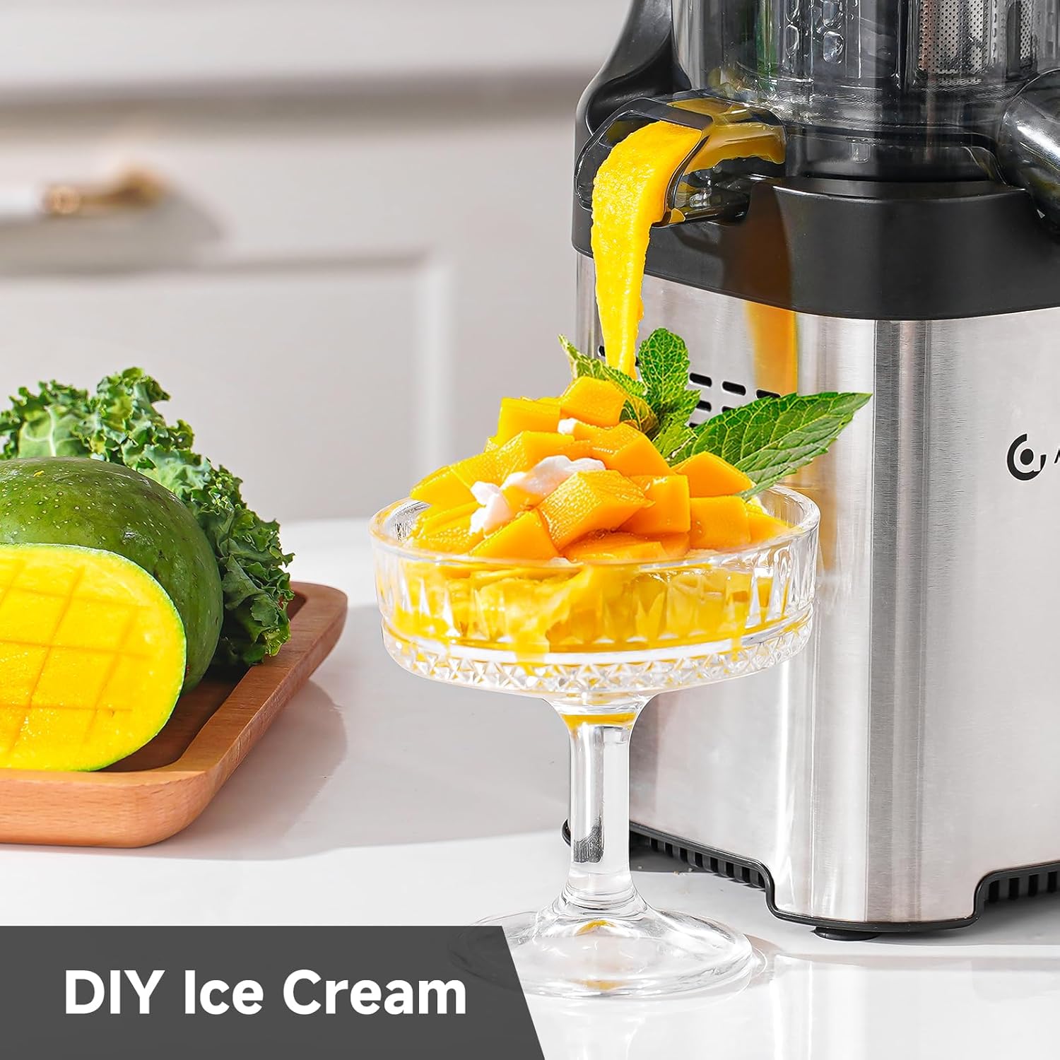 Mango ice cream being poured into a glass with a juicer and mangoes in the background.