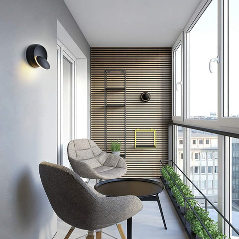 Modern balcony with two chairs, a small table, and a view of city buildings.