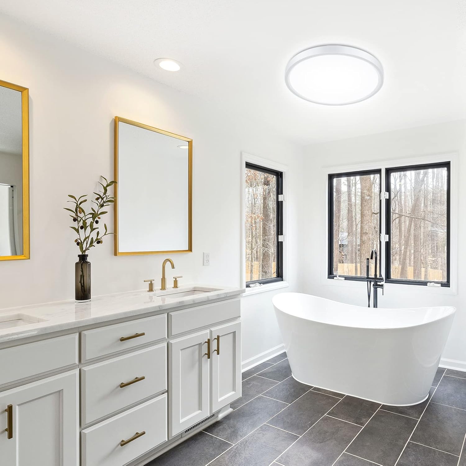 Modern bathroom with white freestanding bathtub, vanity, and large windows.