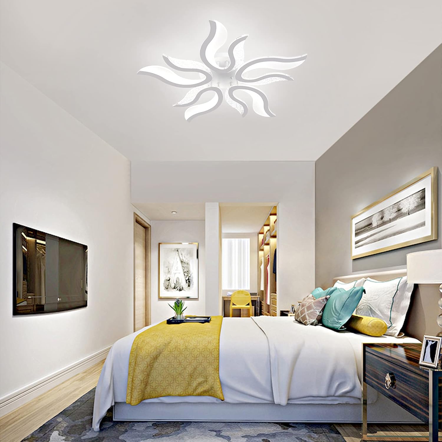 Modern bedroom with a bed, TV, and decorative pillows.