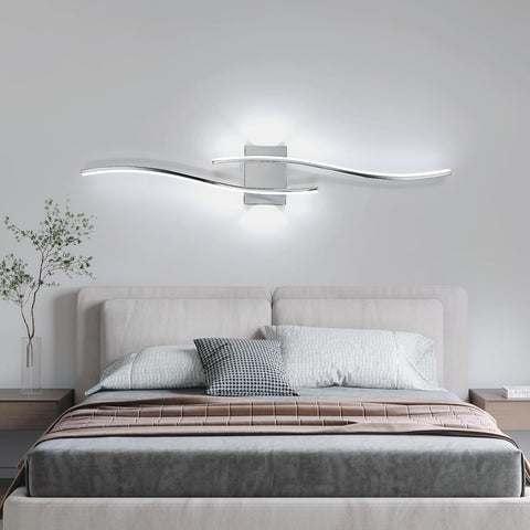 Modern bedroom with a bed, decorative pillows, and a wall-mounted light fixture.