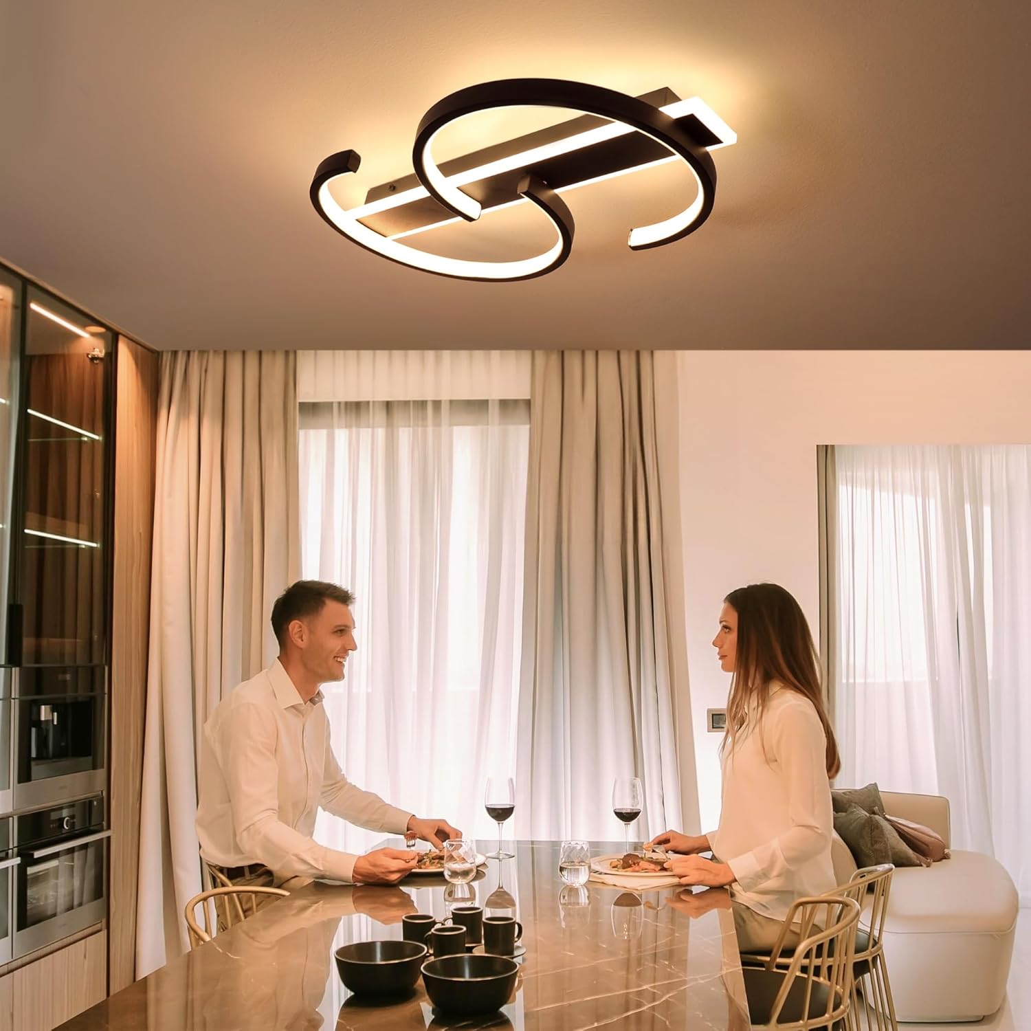 Modern ceiling light fixture in a dining room with two people at a table.