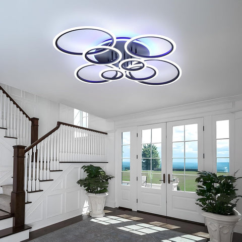 Modern ceiling light fixture in a home interior with staircase and glass doors.