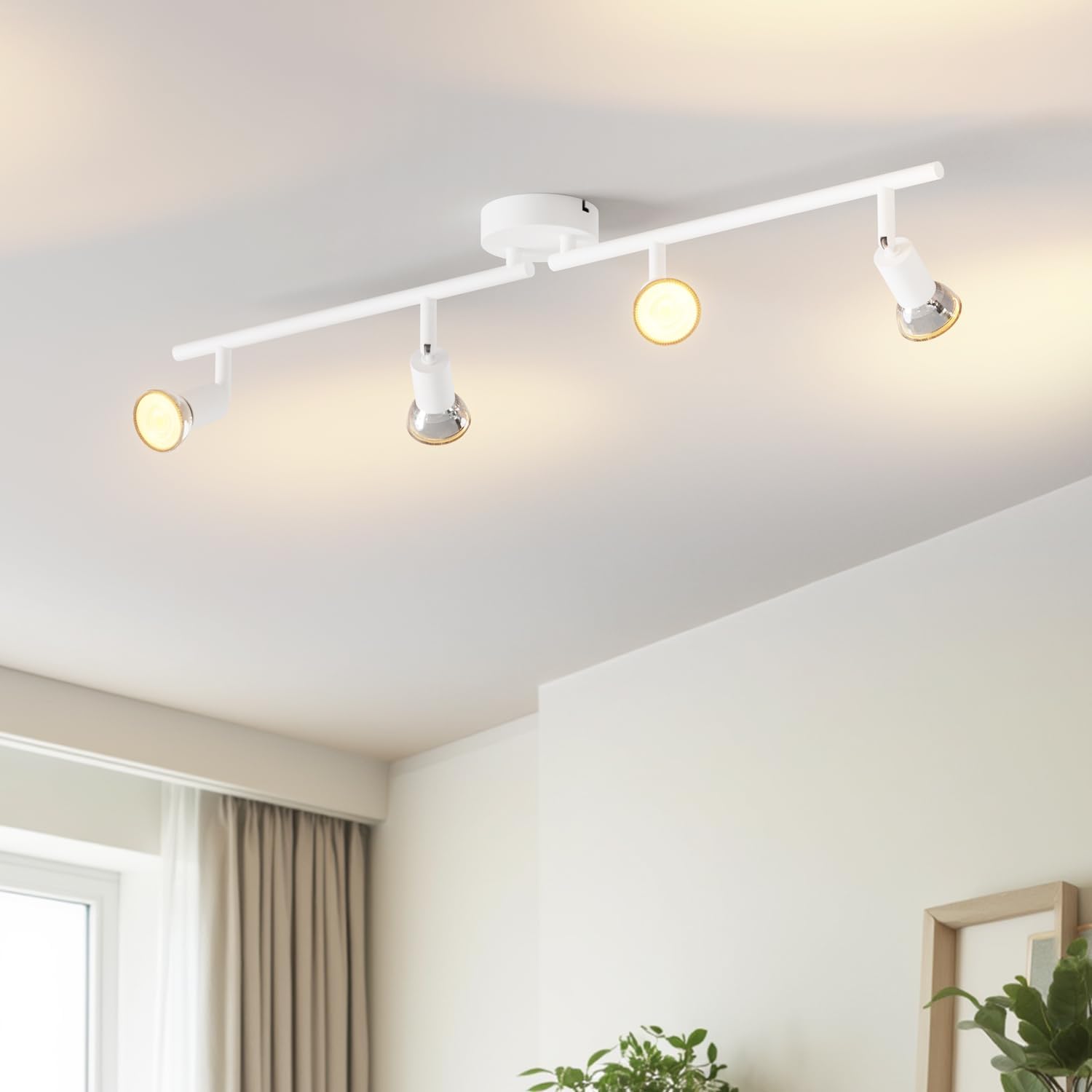 Modern ceiling light fixture with four lights in a room with a window and plants.