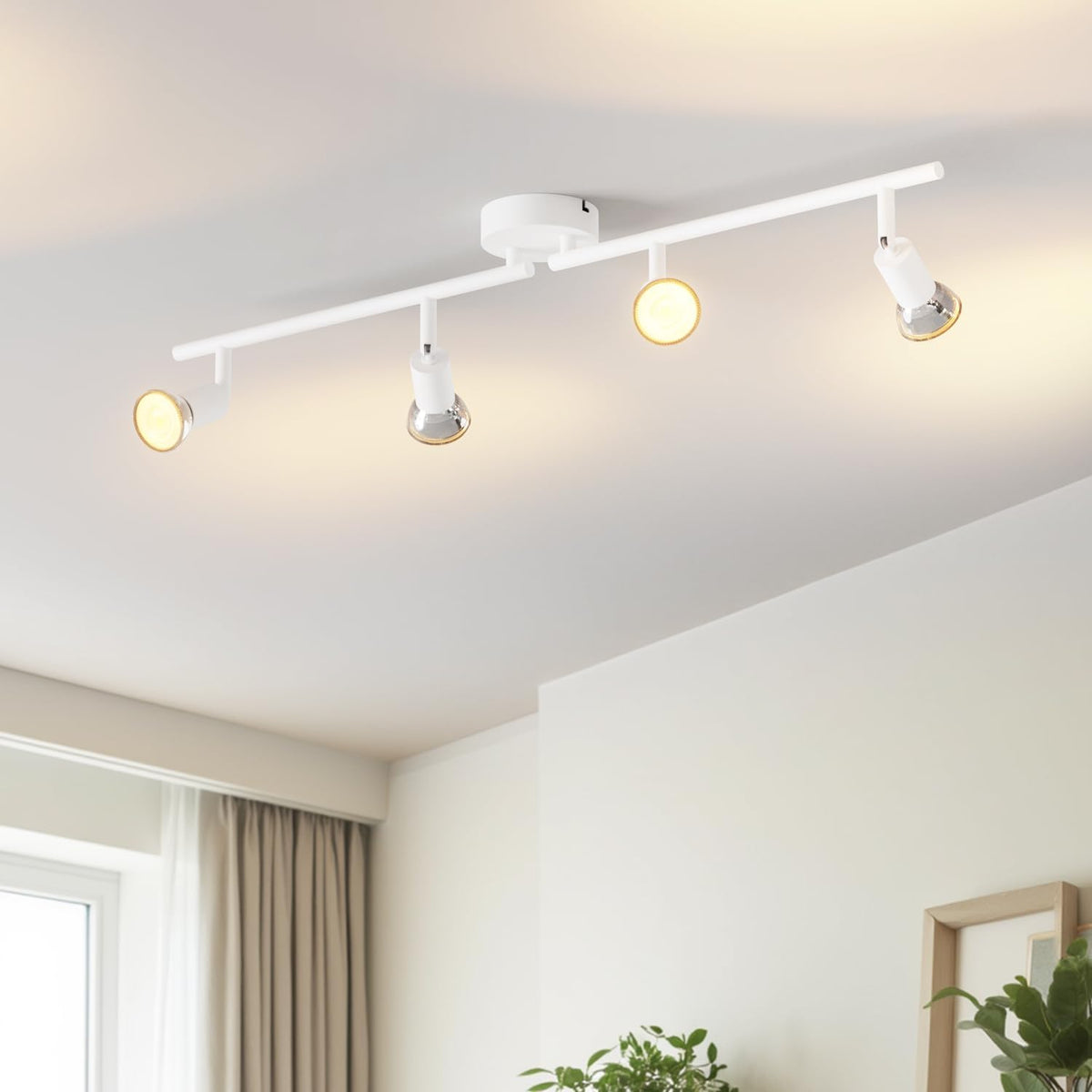 Modern ceiling light fixture with four lights in a room with a window and plants.