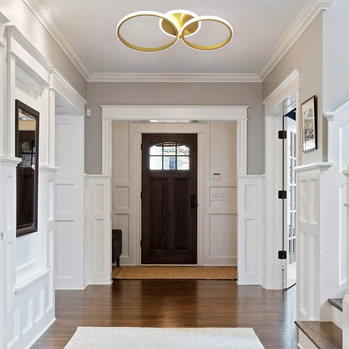 Modern ceiling light fixture with gold and white rings on a neutral background