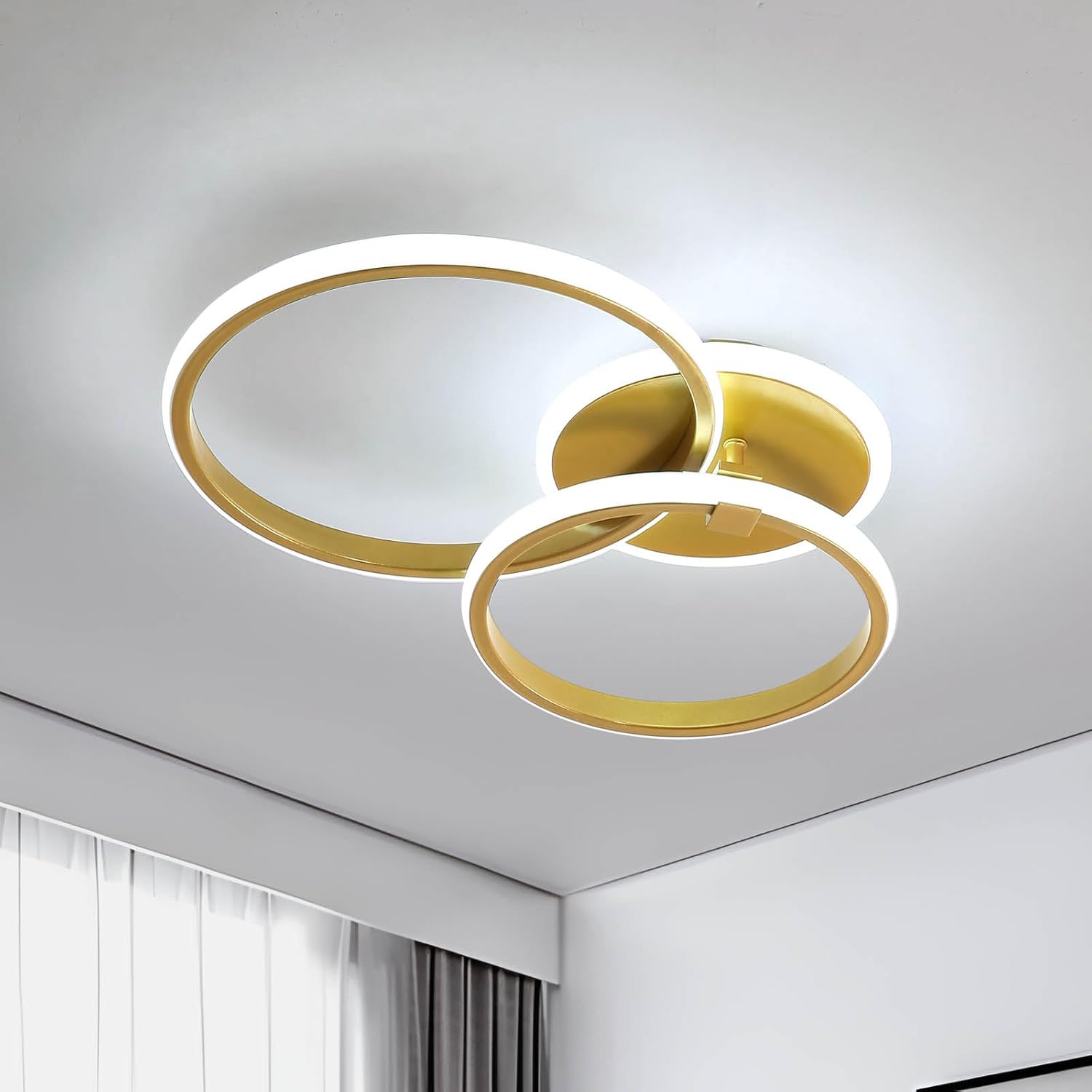 Modern ceiling light fixture with gold and white rings on a neutral background