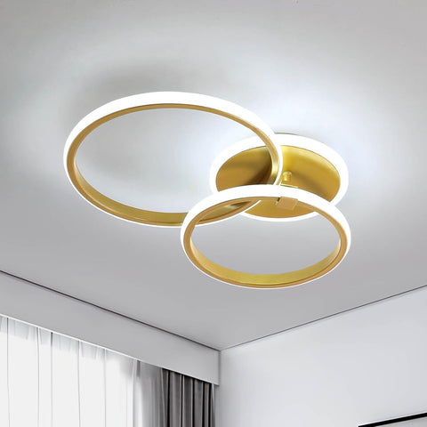 Modern ceiling light fixture with gold and white rings on a neutral background