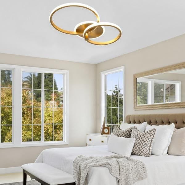 Modern ceiling light fixture with gold and white rings on a neutral background