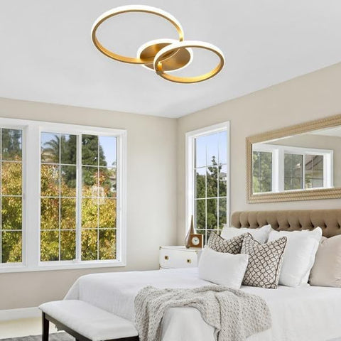 Modern ceiling light fixture with gold and white rings on a neutral background
