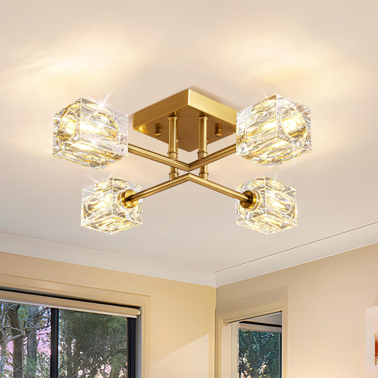 Modern ceiling light fixture with gold finish and crystal-like glass shades in a room with windows.