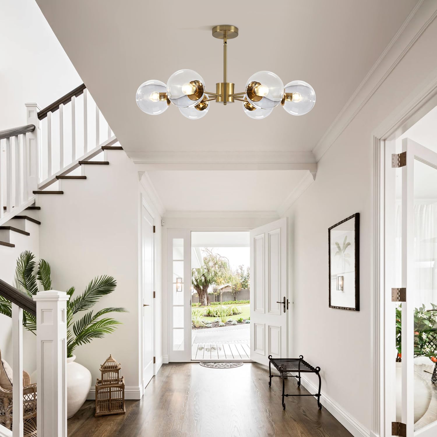 Modern chandelier hanging in a bright living room with white walls and a staircase.