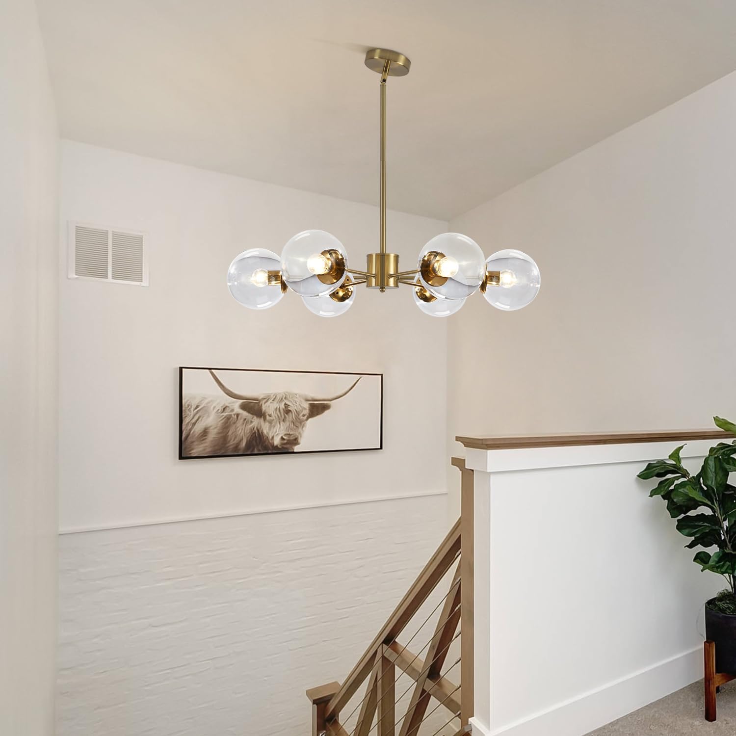 Modern chandelier hanging in a room with a bull artwork on the wall.