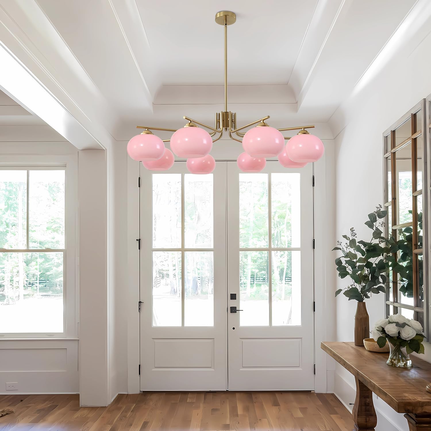 Modern chandelier with pink glass shades in a bright room with wooden floor and white walls.