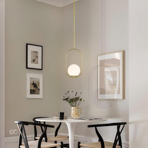 Modern dining room with a white table, black chairs, and a pendant light.