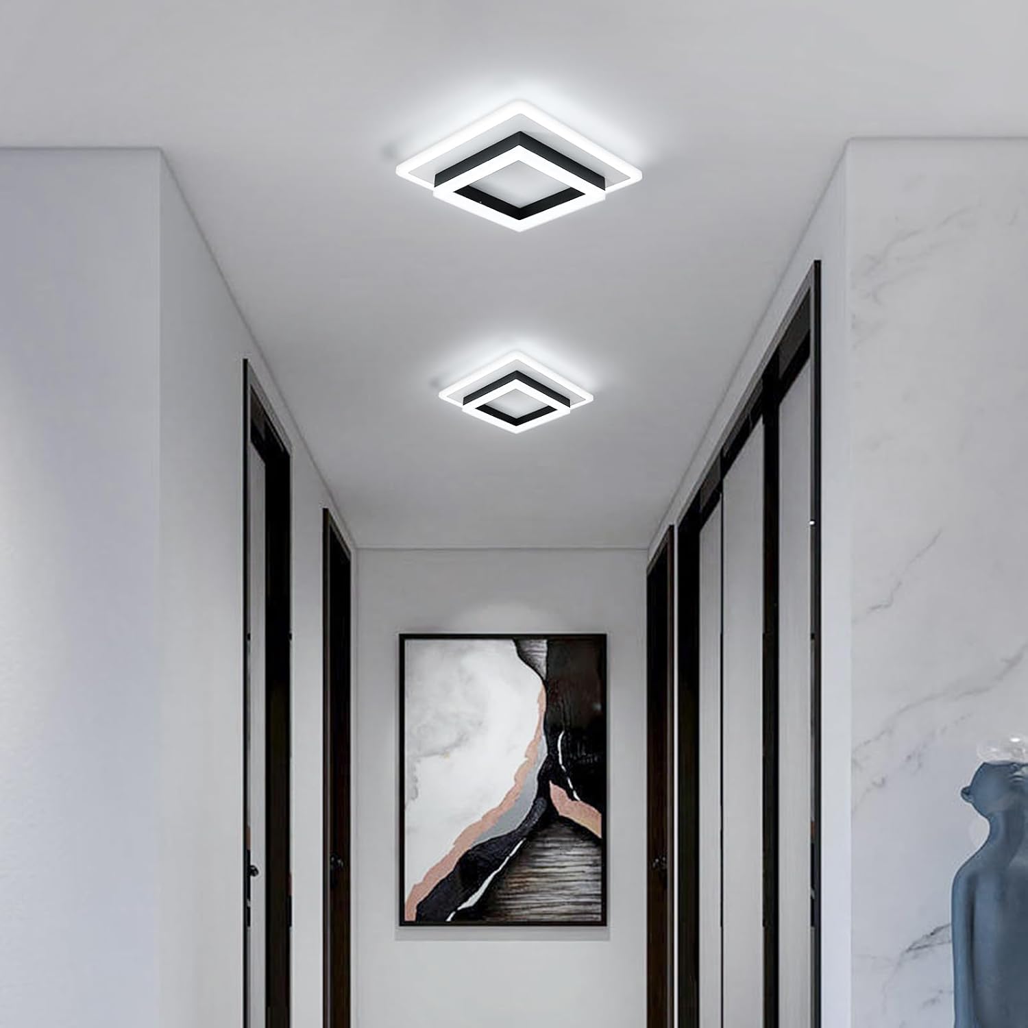 Modern hallway with square ceiling lights, marble wall, and abstract art.