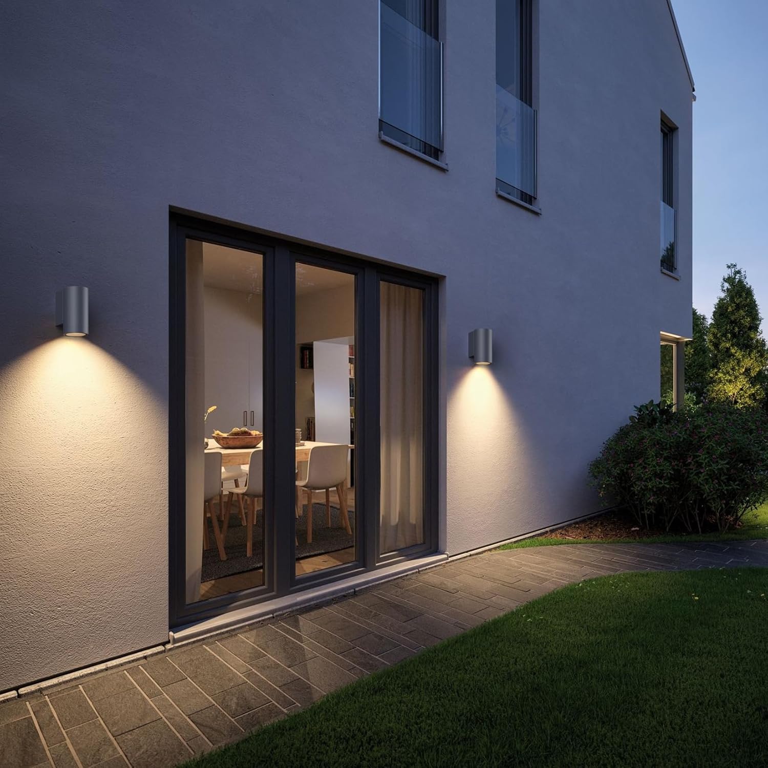 Modern house exterior with large sliding glass door and wall lights at night.