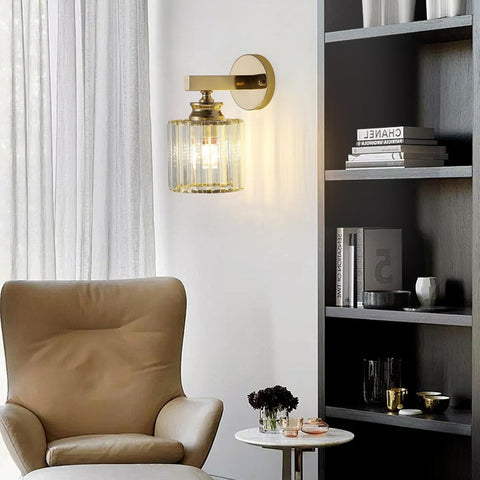 Modern interior with a beige armchair, gold wall sconce, and bookshelf.
