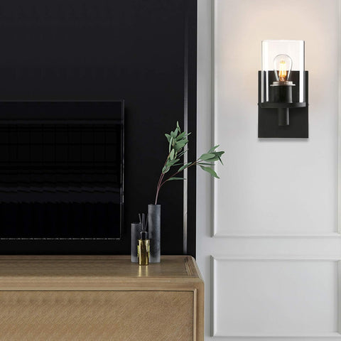 Modern interior with a black wall-mounted light fixture, wooden cabinet, and decorative items.