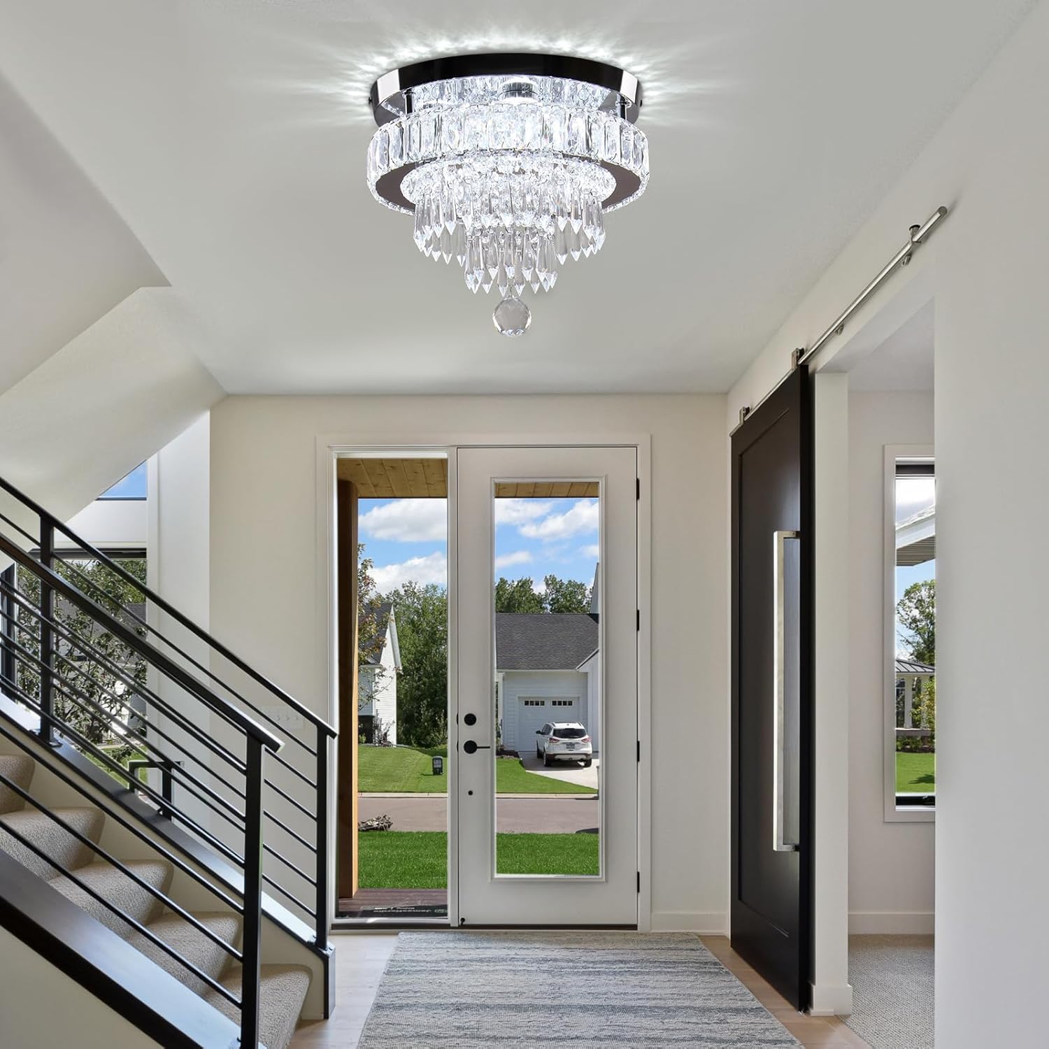 Modern interior with a chandelier, staircase, and view of a house exterior.