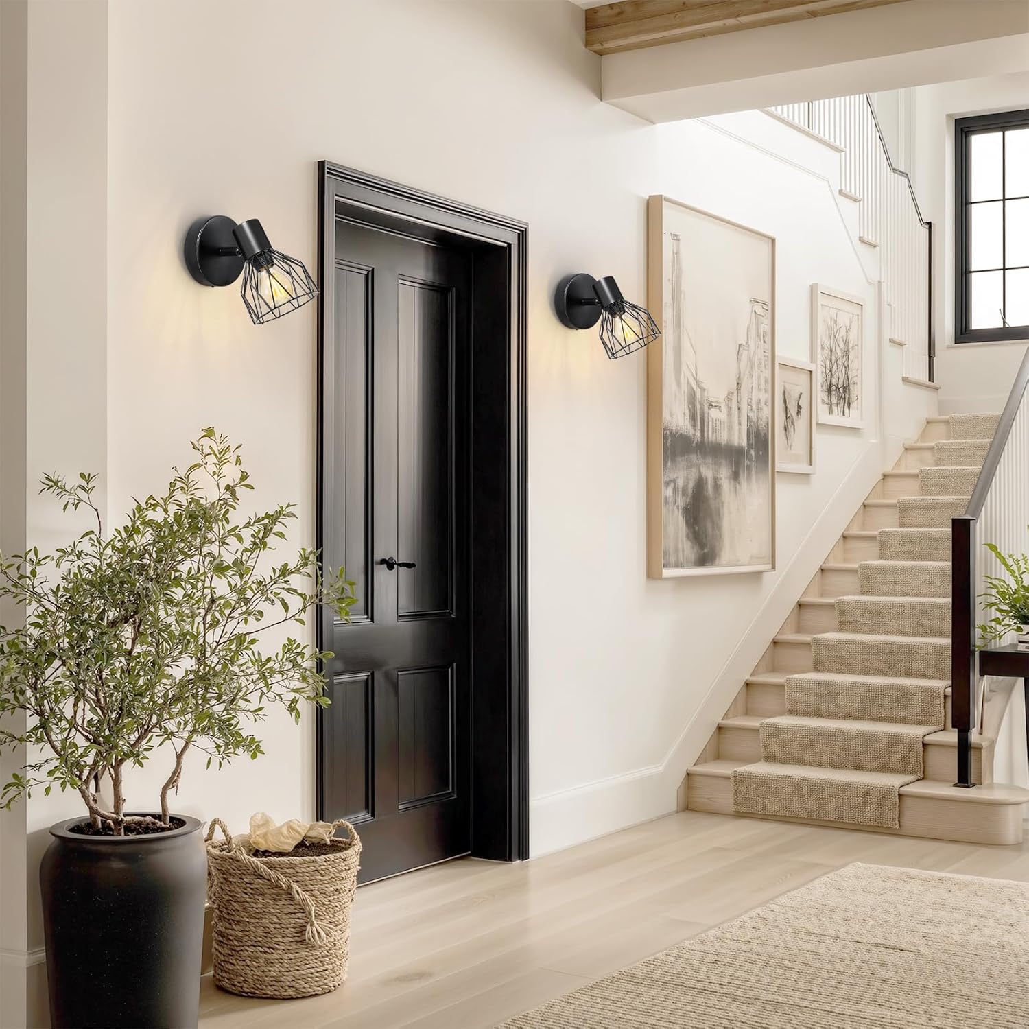 Modern interior with black door, wall sconces, and staircase