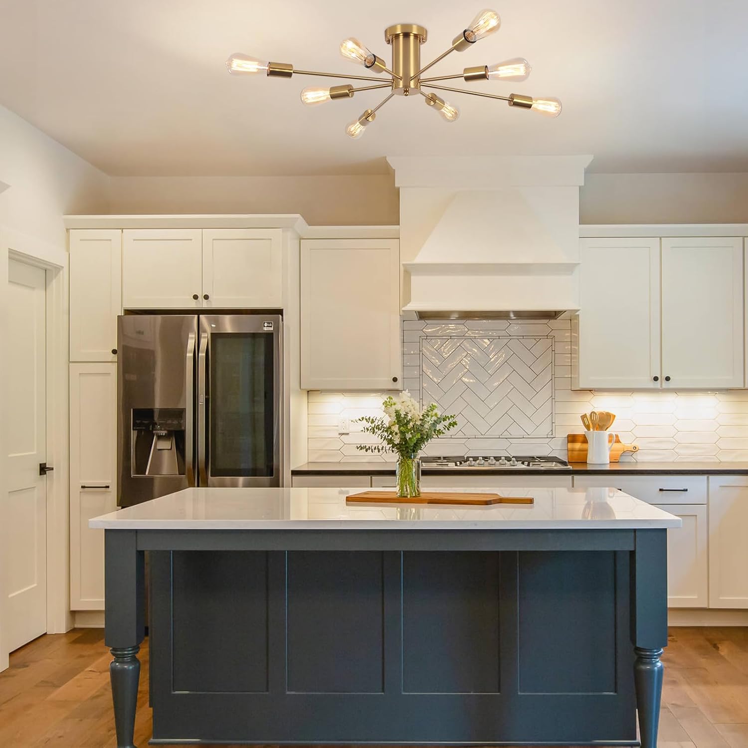 Modern kitchen with a blue island, stainless steel appliances, and decorative lighting.