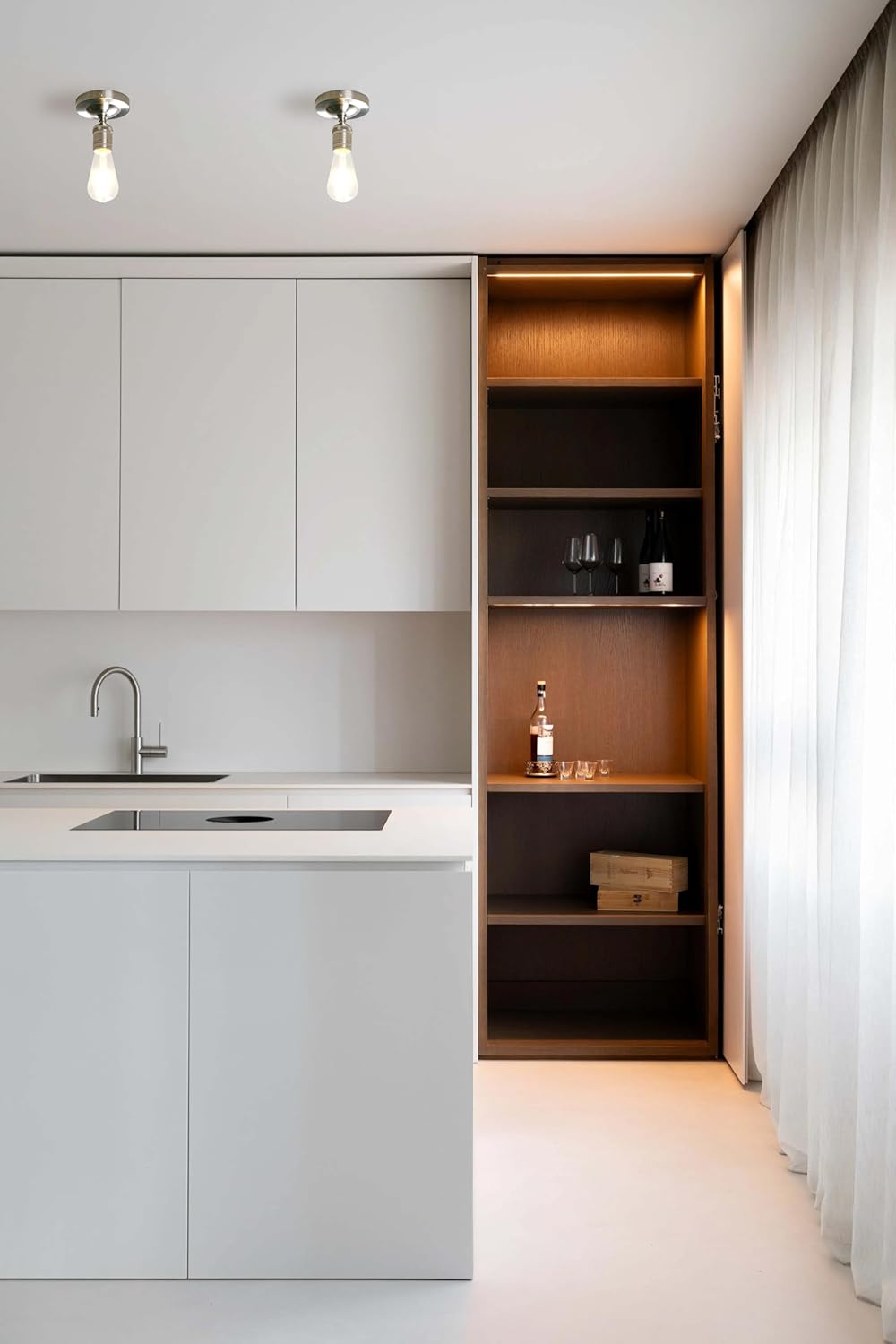 Modern kitchen with open cabinet revealing bar items.