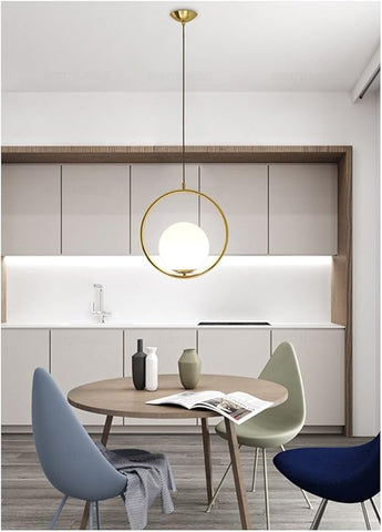 Modern kitchen with round wooden table, chairs, and pendant light fixture.