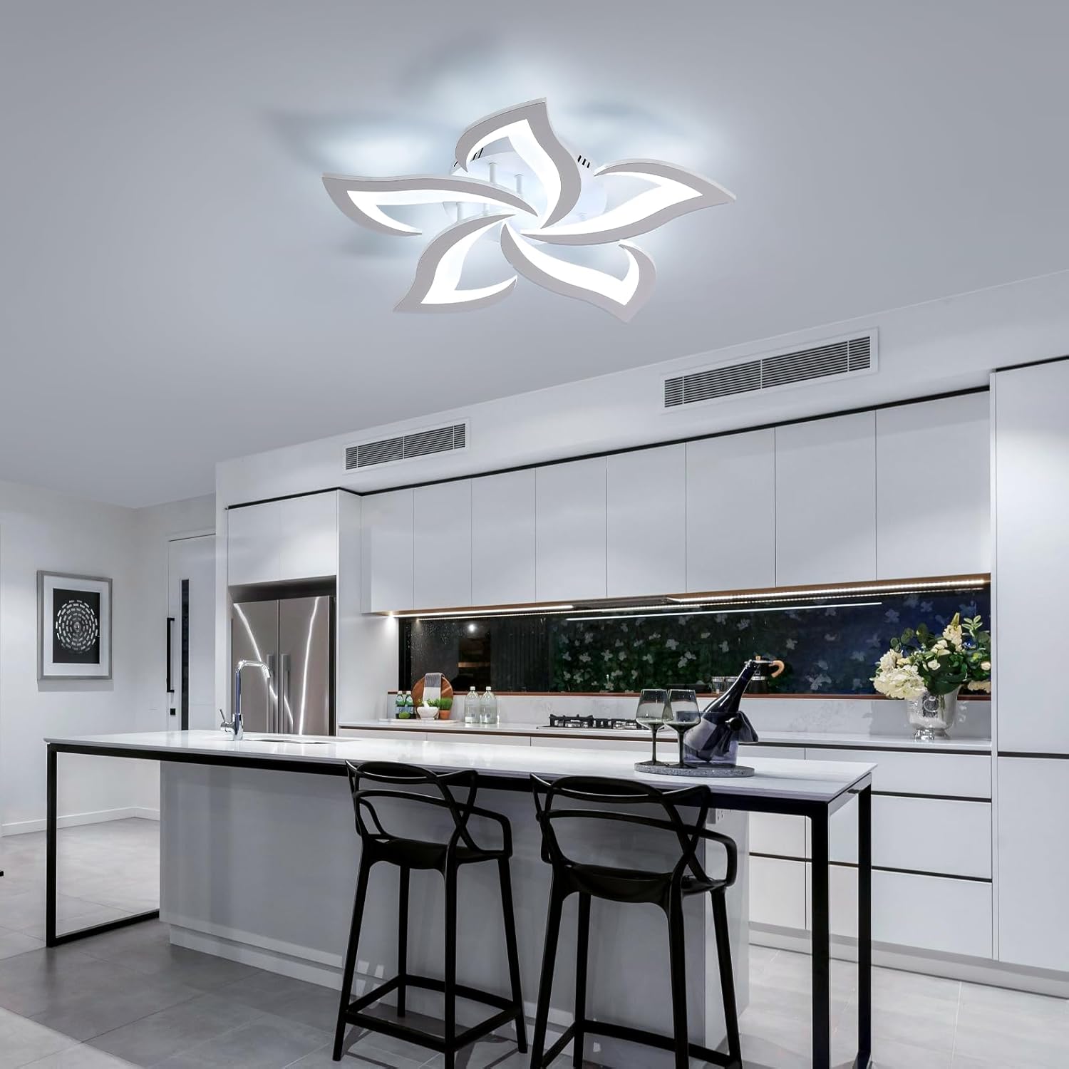 Modern kitchen with white island and black bar stools, featuring a decorative ceiling light.